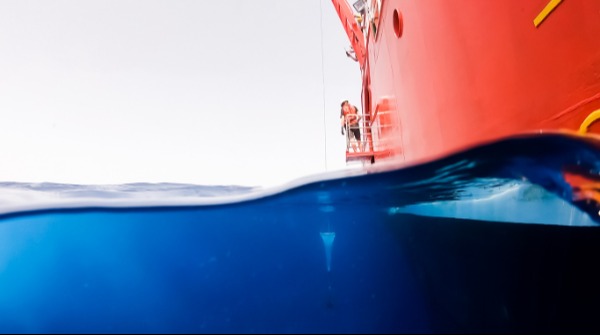 Red ship on blue water view half under water half above