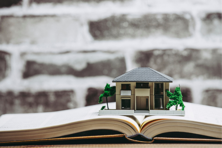 Stock image of a home model miniature sitting on top of an open book