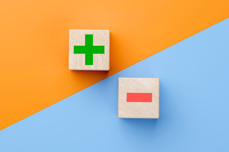 Two wooden blocks on a diagonal orange and blue background; one block has a green plus sign, the other has a red minus sign.